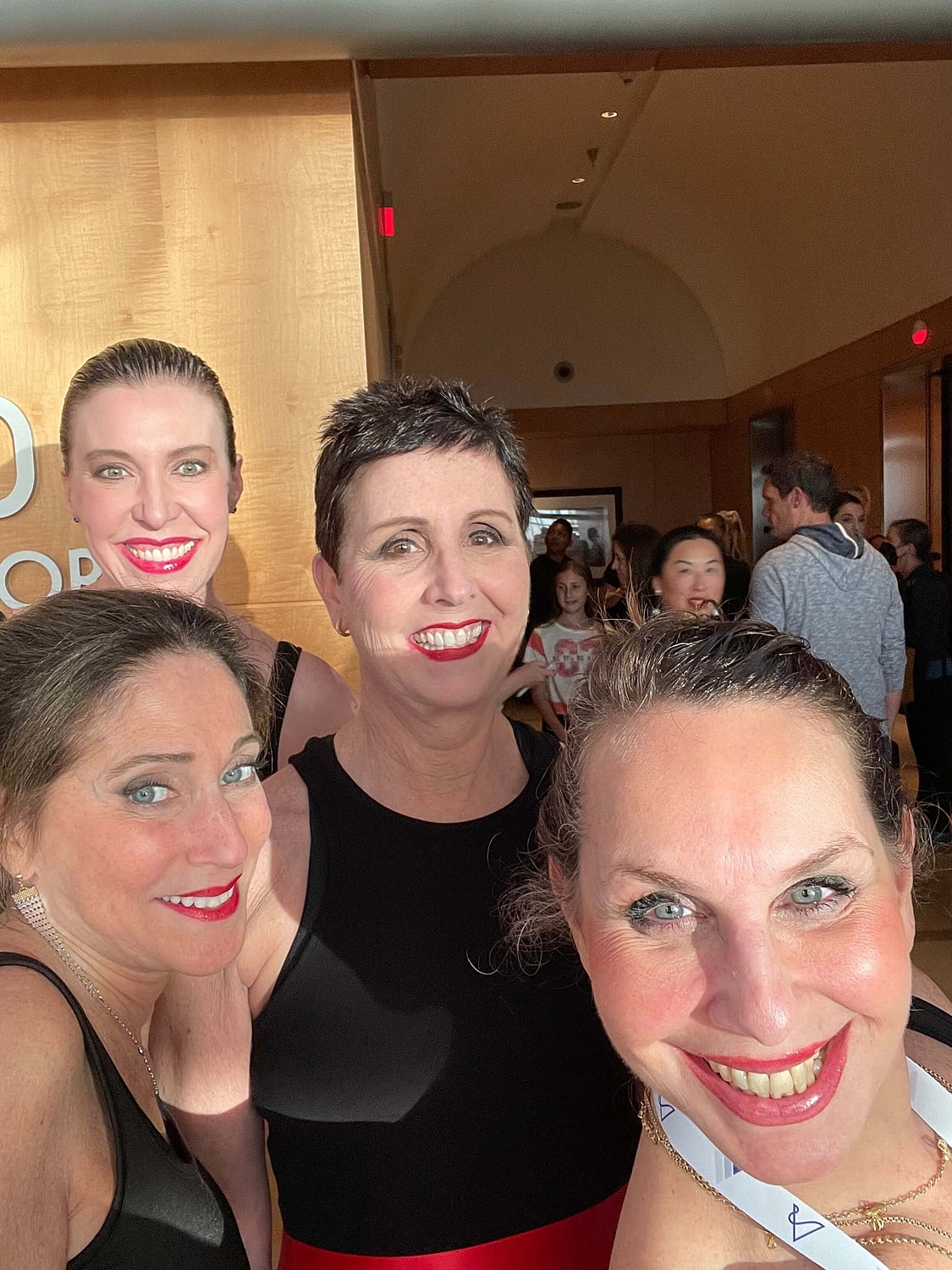 Four women smiling in a vibrant indoor setting.