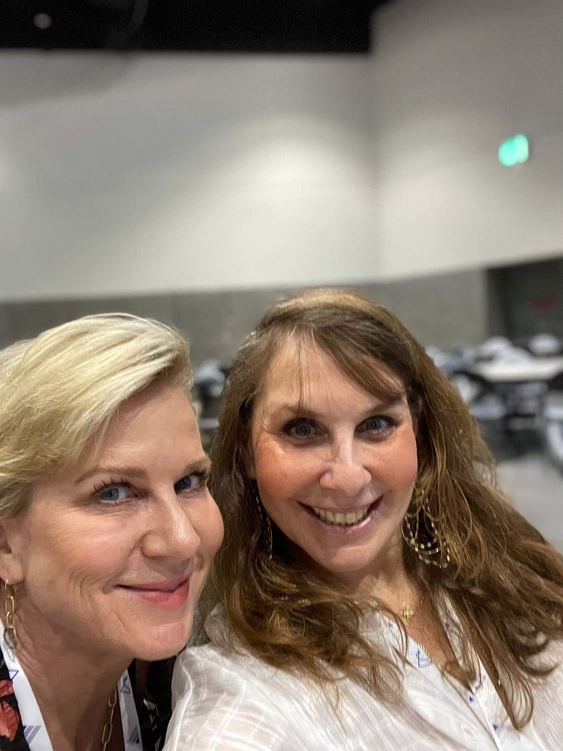 Two women smiling for a selfie indoors.