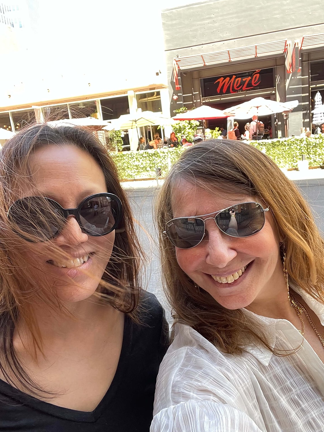 Two friends smiling outside on sunny day.
