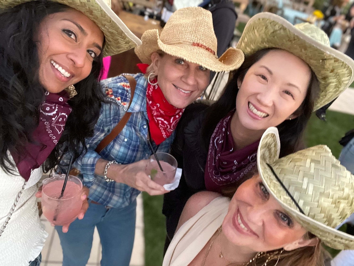 Four friends enjoying drinks in cowboy hats.