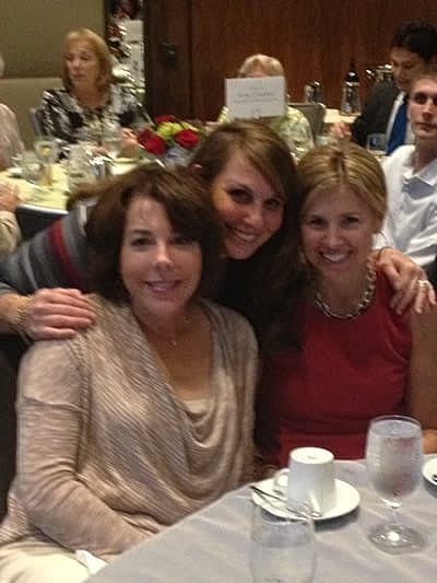 Three women smiling at a social gathering.