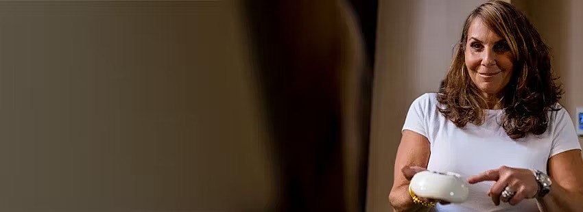 Person holding a device, smiling in a setting.