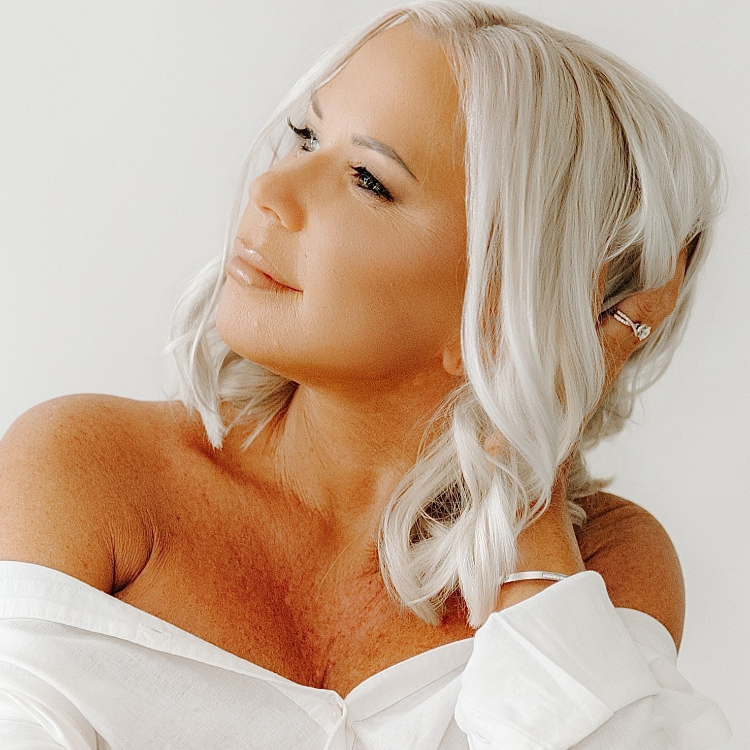 Woman with silver hair in off-shoulder top.