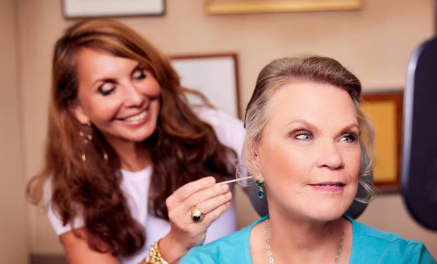 Stylist applying makeup to a smiling client.