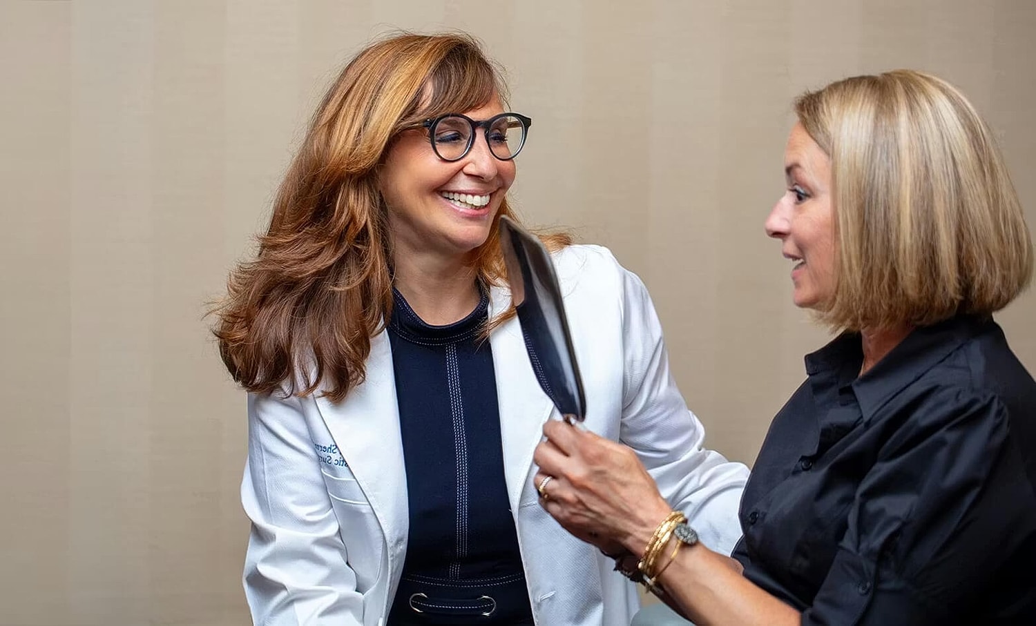 Two women smiling and interacting professionally.