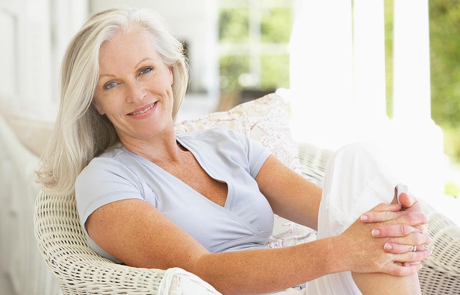 Smiling woman relaxing on a wicker chair.