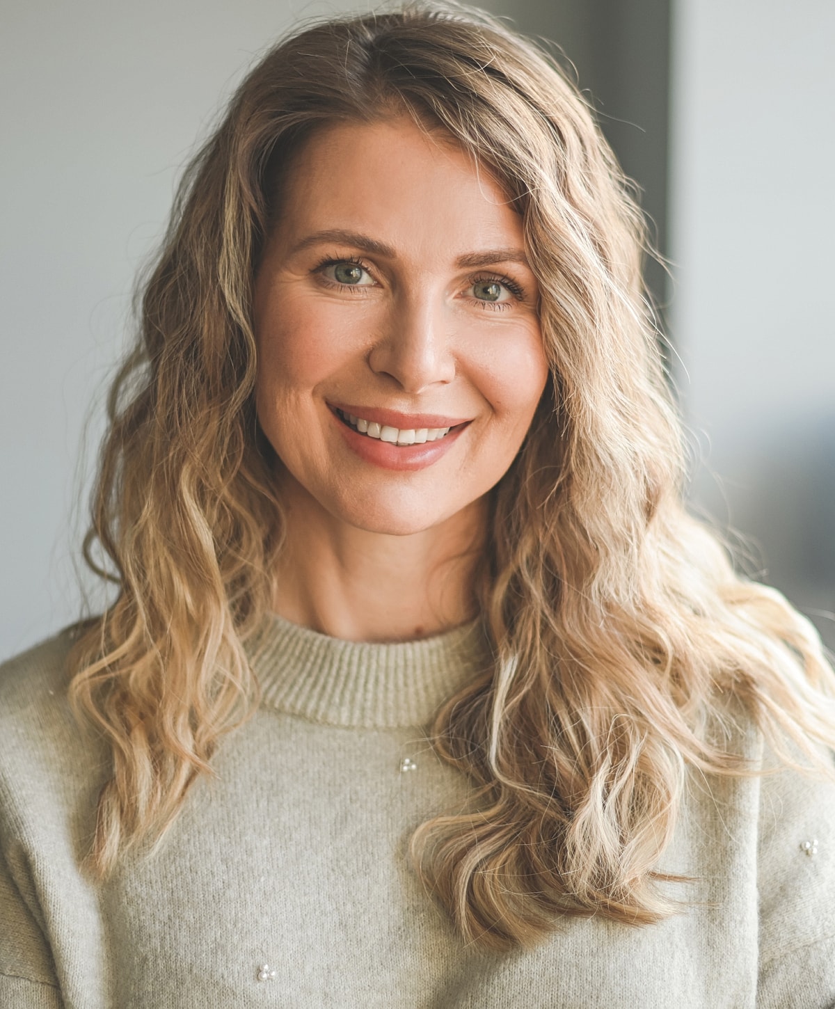 Smiling woman with wavy hair in a sweater.