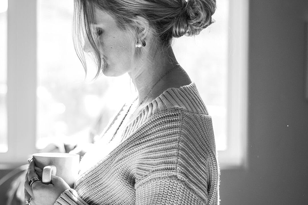 Woman in knit sweater holding a coffee cup.