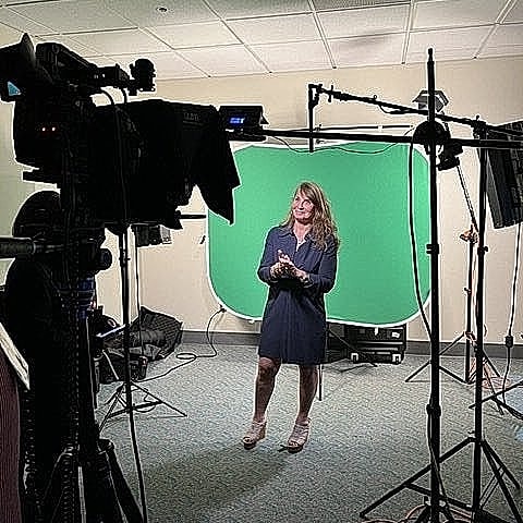 On-set female presenter with a green screen backdrop.