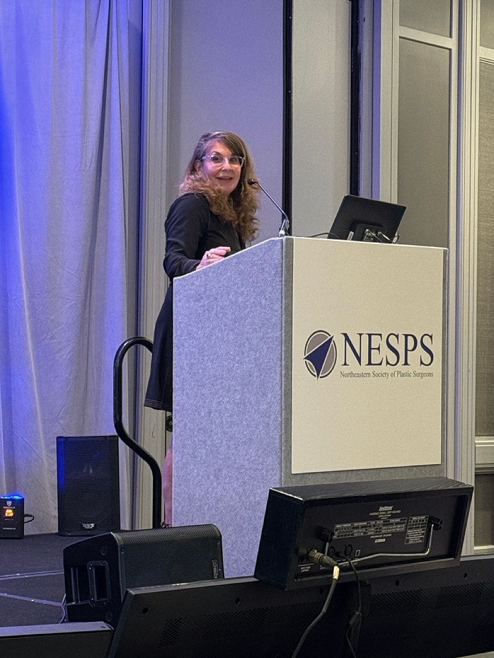 Presenter at a conference podium speaking to audience.