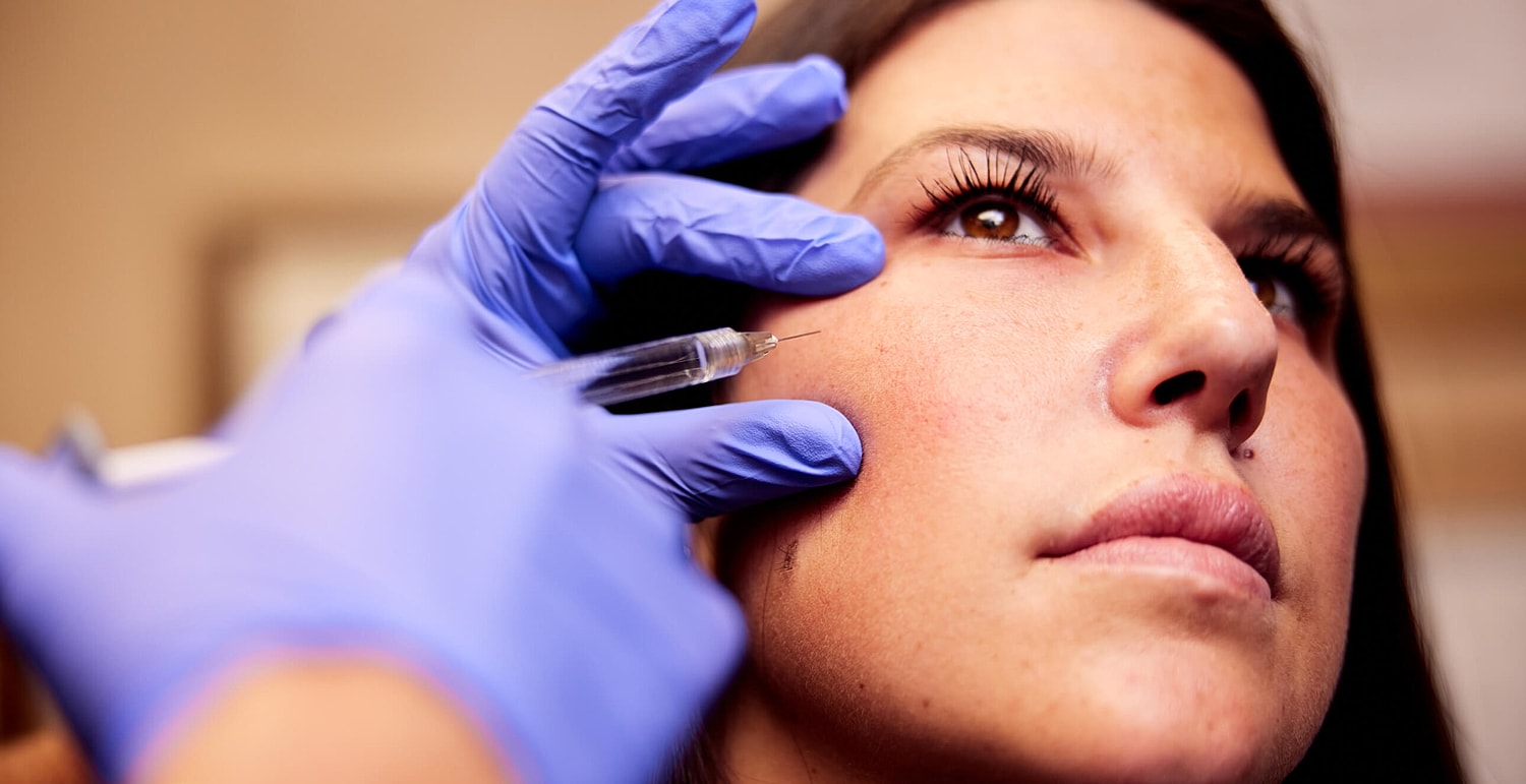 Aesthetic professional administering treatment to client.