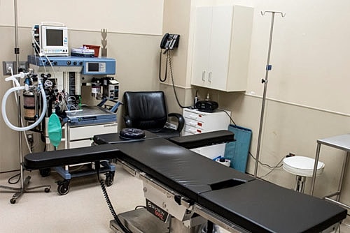 Surgical room with equipment and examination table.