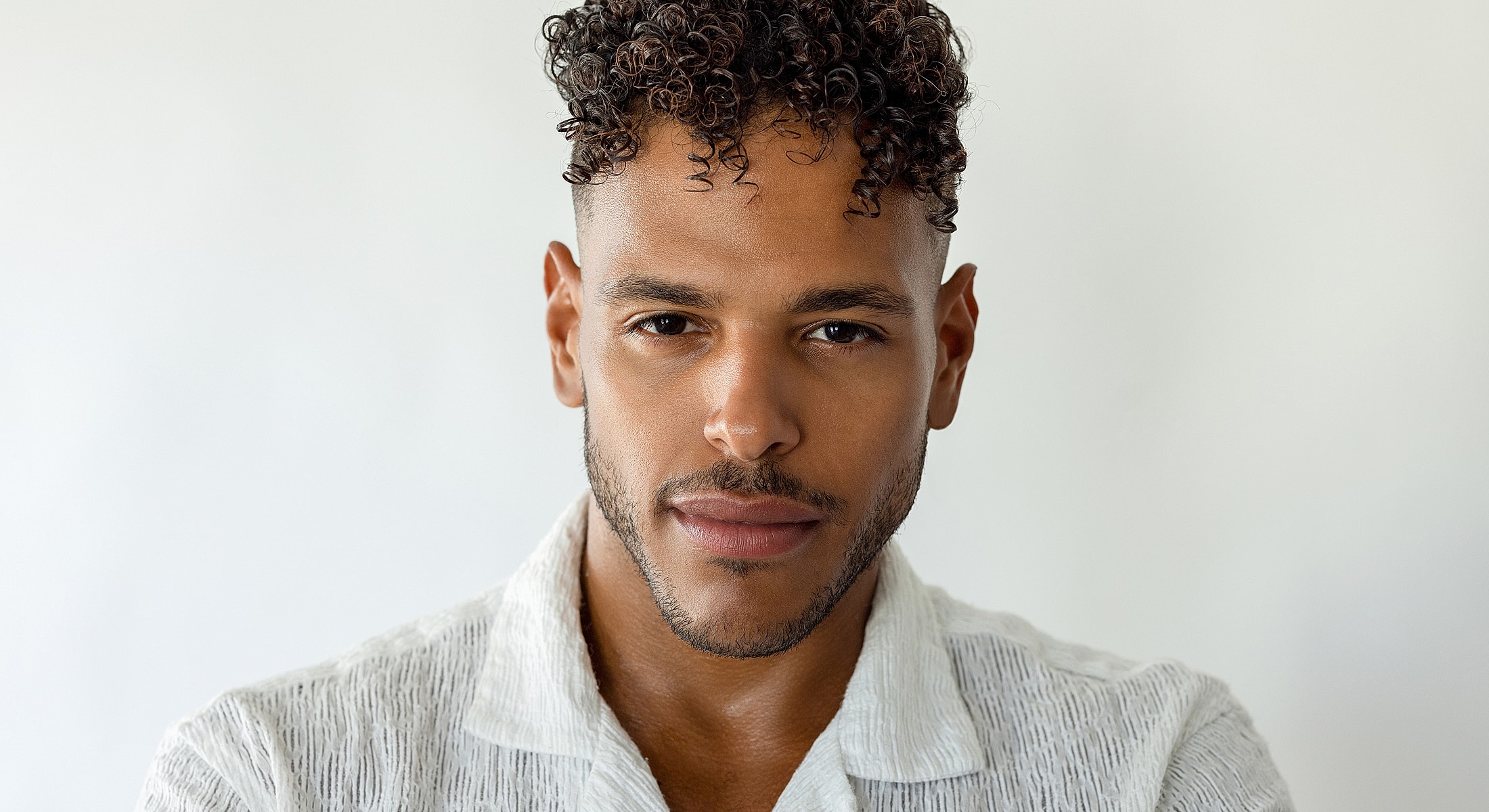 Man with curly hair in a white shirt.