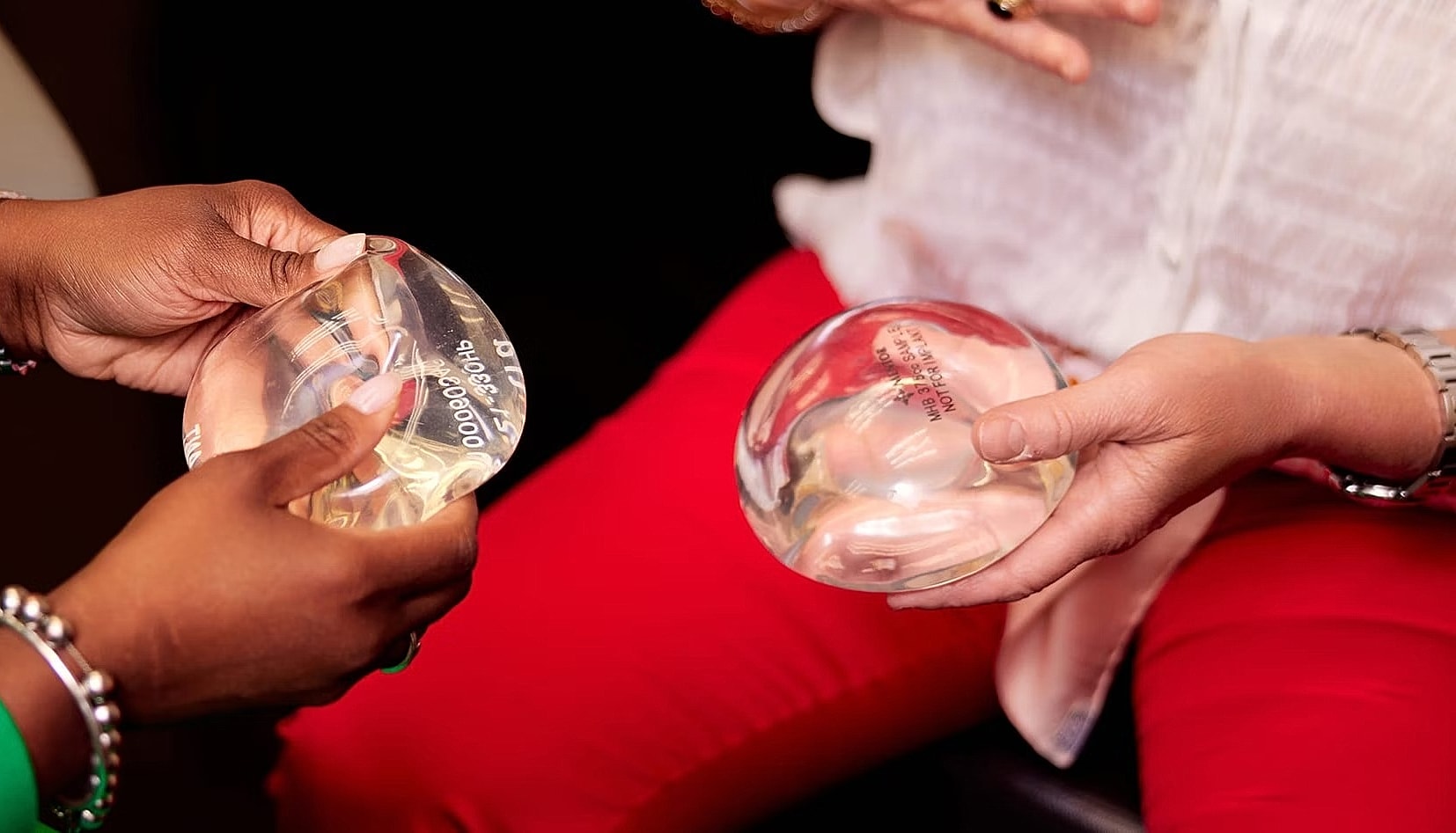 Hands holding breast implant models for discussion.