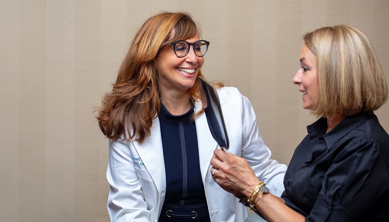 Two women laughing in a professional setting.